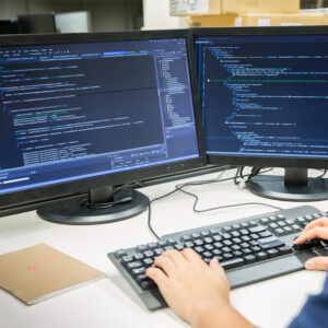 Person working with code on desktop computers