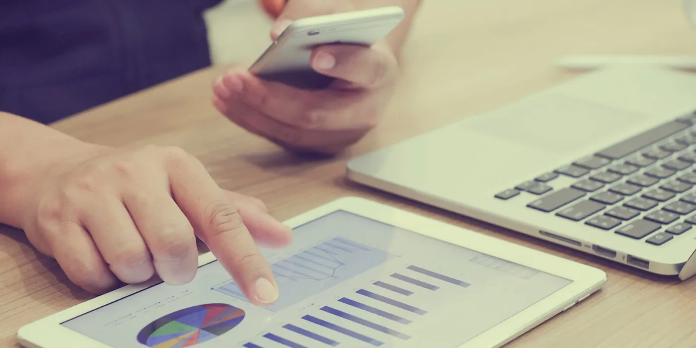 Person on phone and tablet looking at analytics