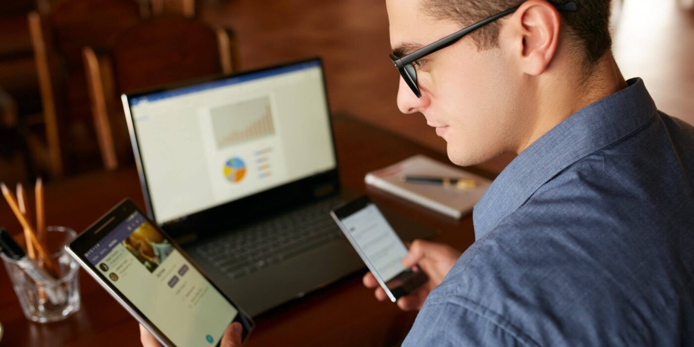 Man working on phone, table and desktop computer