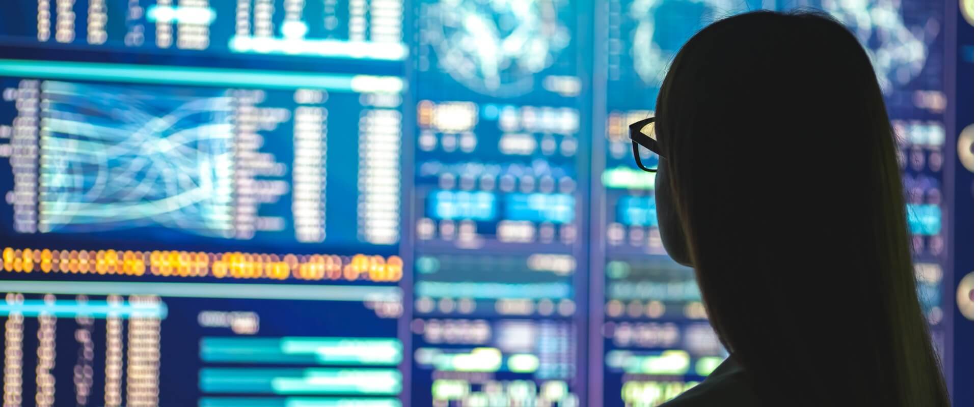 Silhouette of a Female with Glasses Looking at a Screen Showing Data