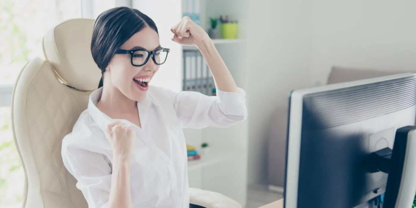 Cheerful woman celebrating at computer