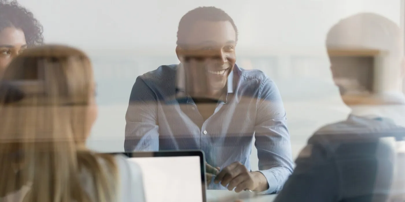 businesspeople negotiating at boardroom view through glass wall