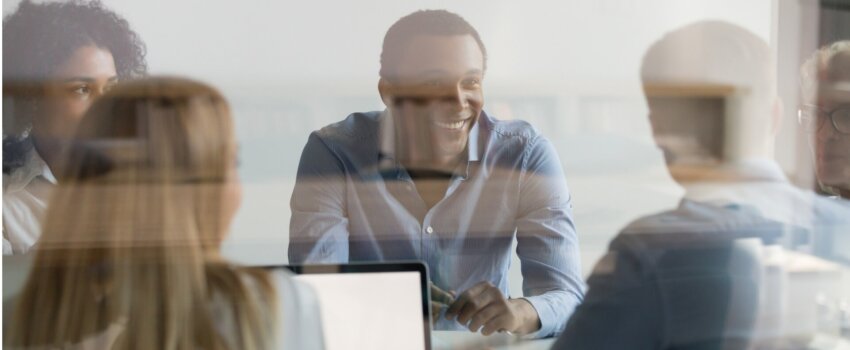 businesspeople negotiating at boardroom view through glass wall