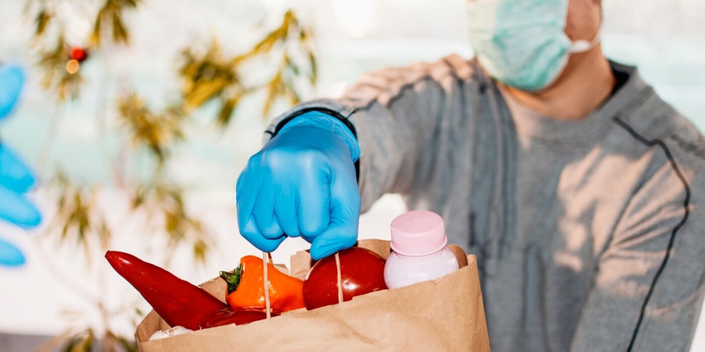 Man wearing mask delivering food in paper bag