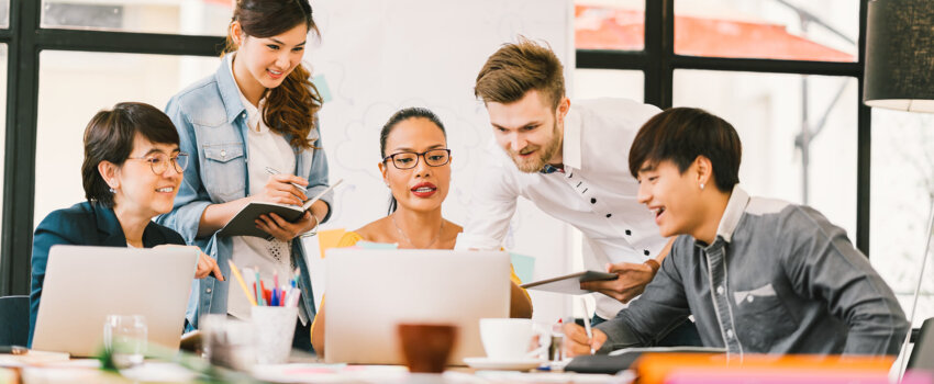 Company Employees gathering around laptop