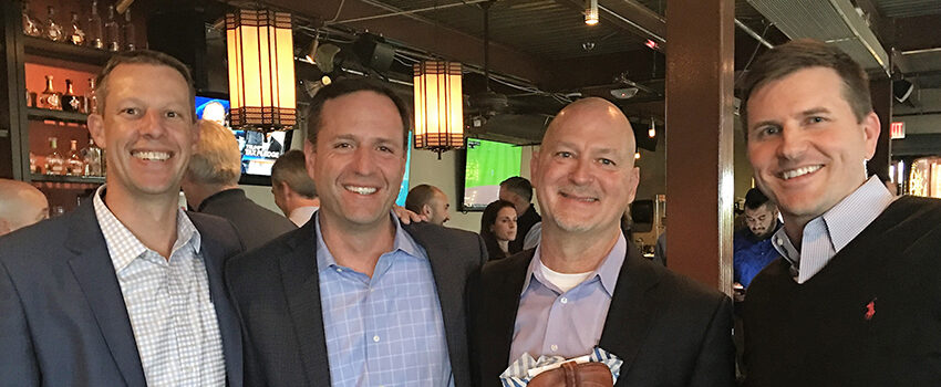 Jason Hansen, Kirk Mielenz, Michael Turner, and Robert Sunker smile for the camera at a party.