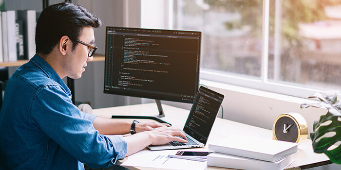 Young Asian programmer coding in his home office