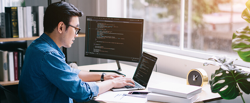 Young Asian programmer coding in his home office