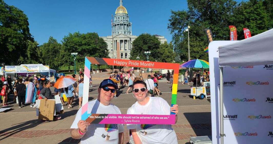 Two RevGen Volunteers pose in front of the Colorado State Capital as they volunteer at the Denver Pride Festival