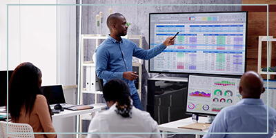 A consultant reviews a color coded spreadsheet with attentive staff