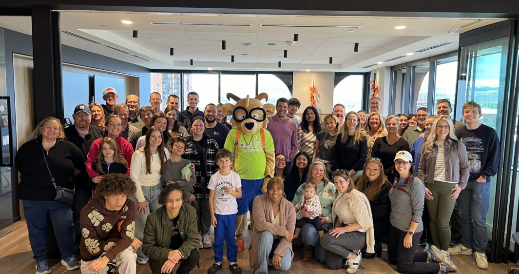 RevGeners and their families pose with the DSF mascot at the 2024 Holiday Volunteer Event