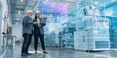 Two factory supervisors look at a tablet that projects a holographic AI service blueprint