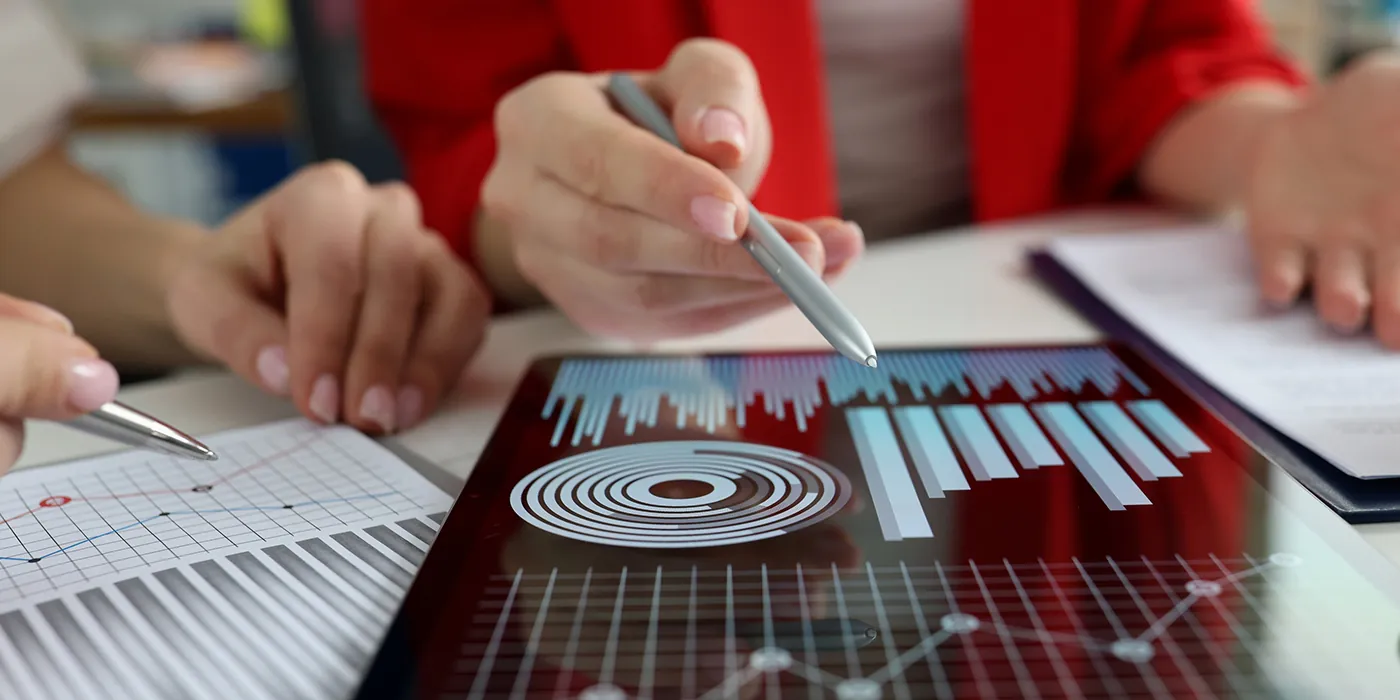 Business women studying charts and diagrams on digital tablet closeup