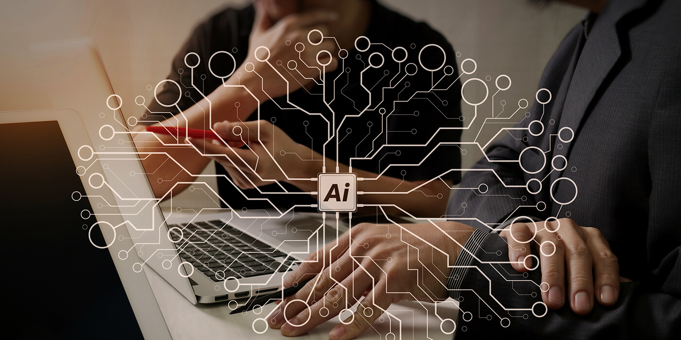 Coworkers sit side by side. An icon of a circuit board labeled AI, with circuits expanding off of it is overlaid on the image.